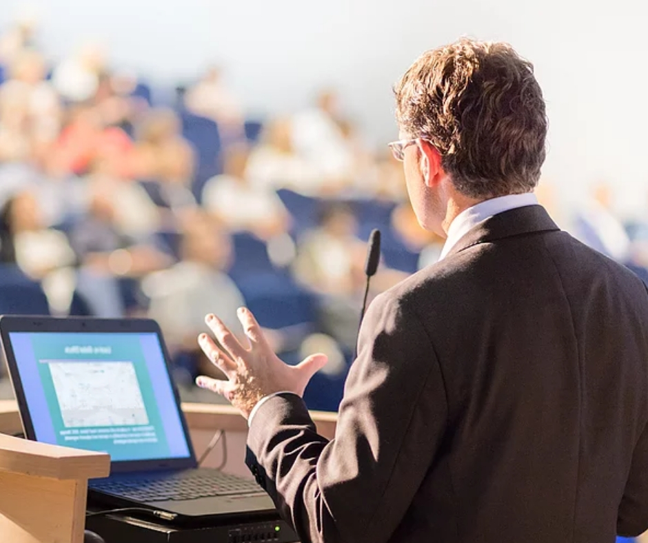 man public speaking in front of crowd